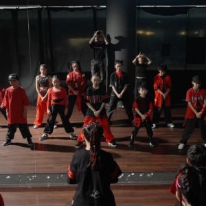 hip-hop-dance-group-rehearsing-in-front-of-studio-mirror Group of kids in red and black street style outfits practicing a dance routine in front of a mirror in a studio