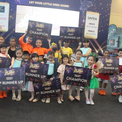Ensemble of young boys and girls in colorful performance outfits posing together with their Champion and Runner Up placards