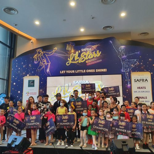 Large gathering of student performers, parents, and instructors filling the stage while displaying numerous competition award boards