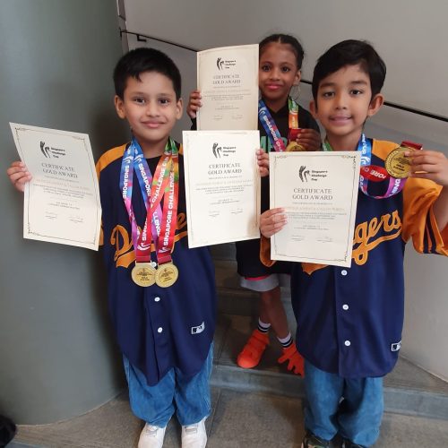 Three young award-winning students wearing medals and matching baseball jerseys holding official gold certificates