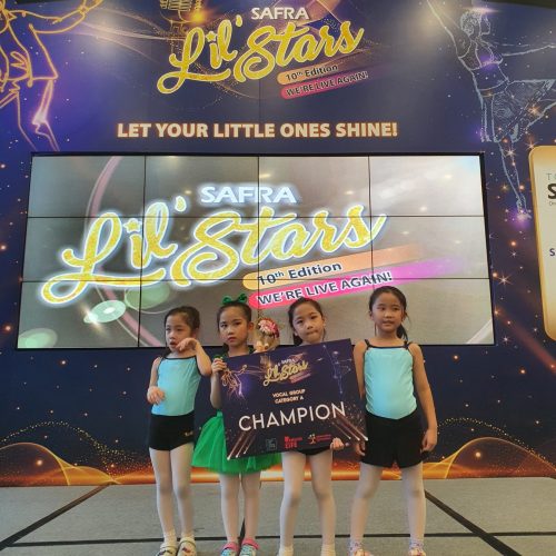 Four young girls in dancewear holding a SAFRA Lil Stars Vocal Group Category A champion award board on stage