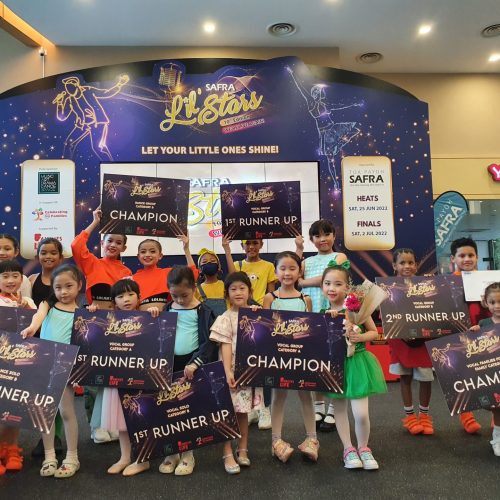 Group of young singing and dancing competitors holding various Champion and Runner Up award boards during an event photo