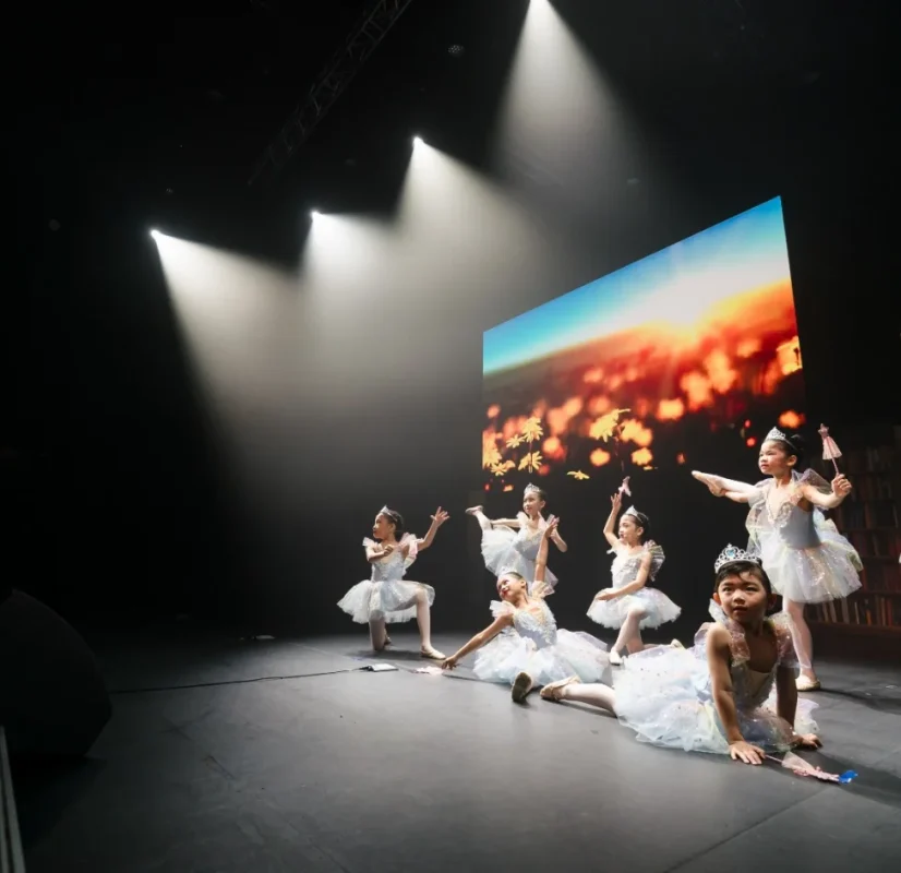 young-ballerinas-performing-ballet-recital-under-spotlights Group of young girls in sparkling light-blue tutus and tiaras performing ballet choreography under bright spotlights